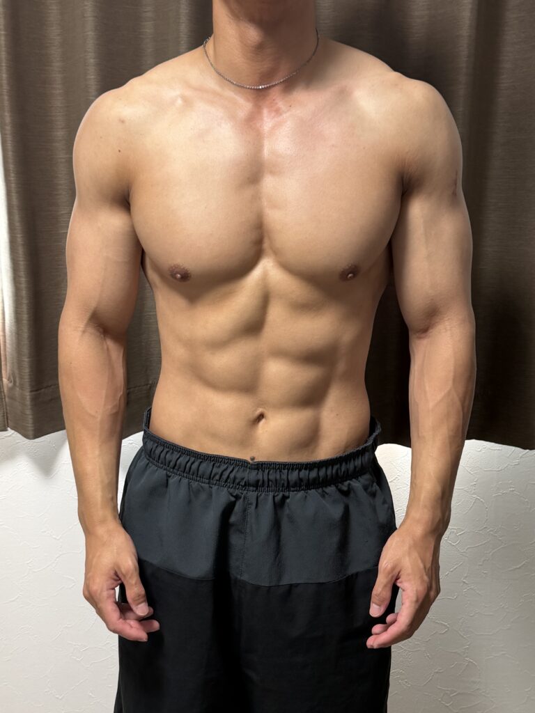 減量24週目の正面写真。体重70.0kg、体脂肪率7.7%。腹筋の溝が深くなり、腕の血管やウエストの引き締まりが分かる状態。