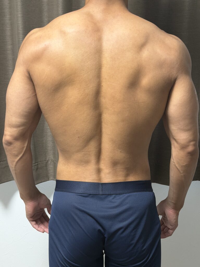 減量26週目の背面写真。広背筋のラインや肩周りの立体感が増し、ウエストが細く逆三角形のシルエットが際立っている。